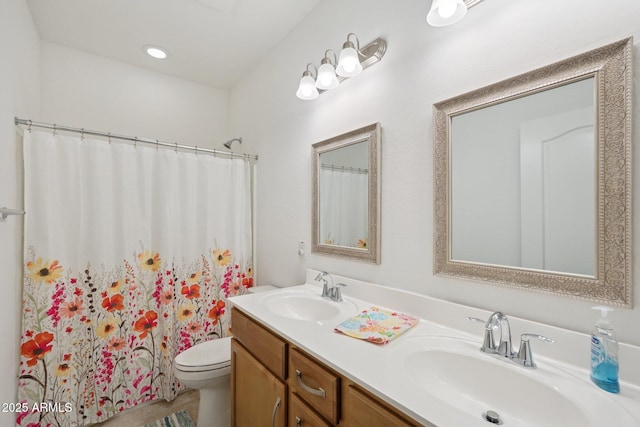 bathroom with double vanity, curtained shower, a sink, and toilet