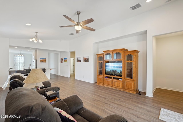 living area with ceiling fan with notable chandelier, visible vents, recessed lighting, and wood finished floors