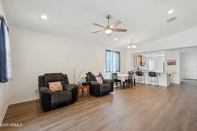 sitting room with lofted ceiling, ceiling fan with notable chandelier, wood finished floors, visible vents, and baseboards