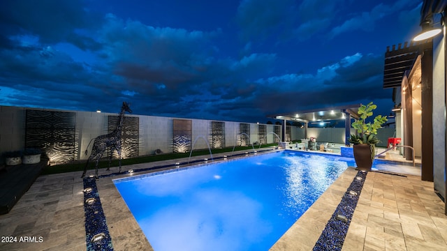 pool at twilight with pool water feature and a patio area