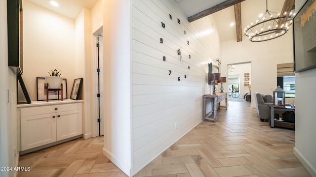 hall with high vaulted ceiling, beam ceiling, light parquet floors, and a chandelier