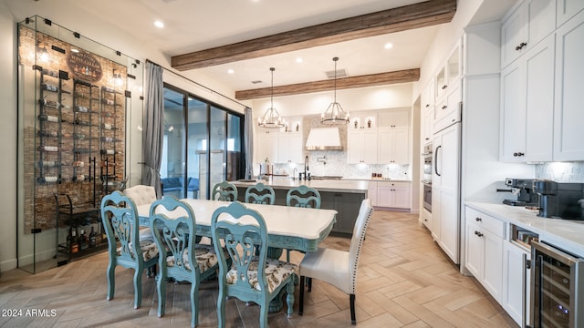 dining area featuring light parquet floors, beam ceiling, sink, and beverage cooler