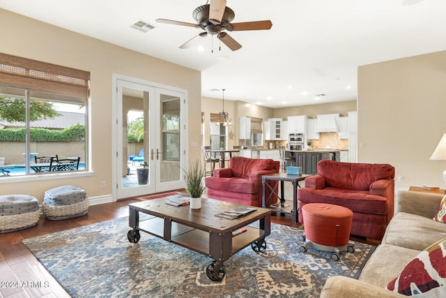 living room with dark hardwood / wood-style floors, ceiling fan with notable chandelier, and french doors