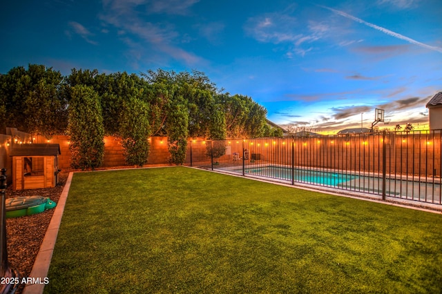 yard at dusk with a fenced in pool and a fenced backyard