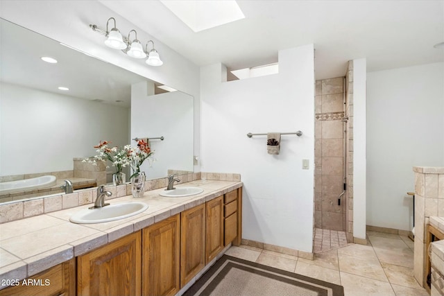 full bath featuring a skylight, a shower stall, tile patterned flooring, and a sink