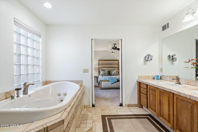 ensuite bathroom featuring visible vents, baseboards, ensuite bath, a jetted tub, and vanity