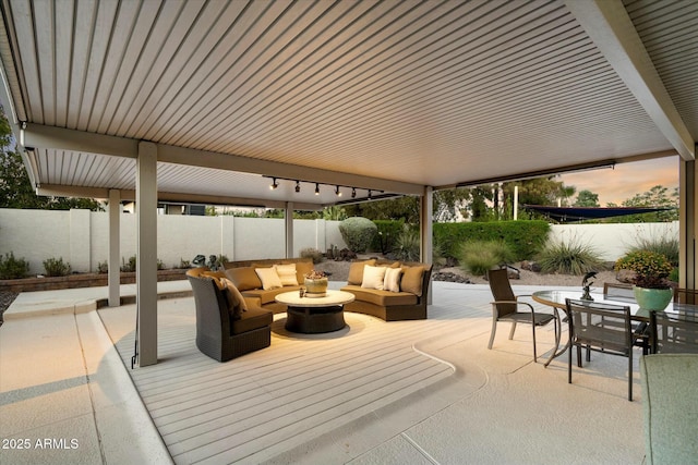 patio terrace at dusk featuring outdoor dining space, outdoor lounge area, and a fenced backyard