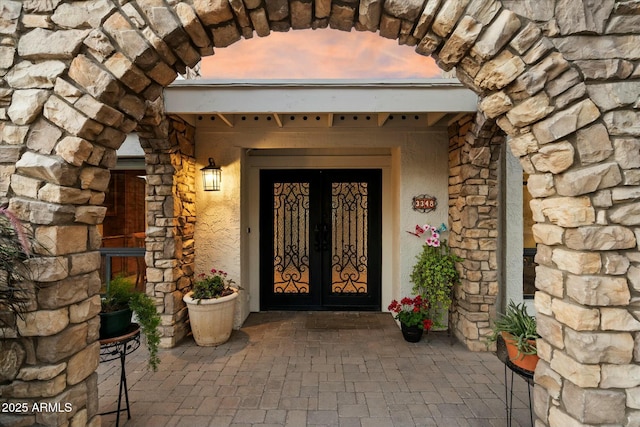 doorway to property featuring stone siding and stucco siding