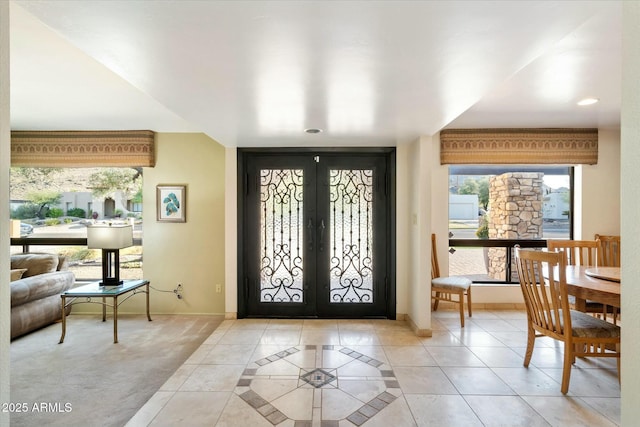 foyer entrance with light tile patterned floors, french doors, and baseboards