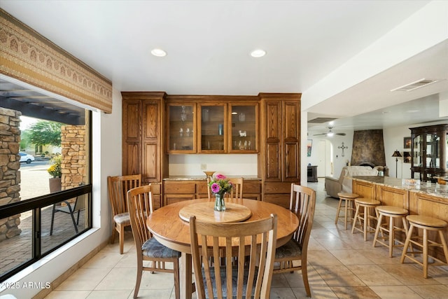 dining space featuring a fireplace, visible vents, a ceiling fan, and light tile patterned flooring