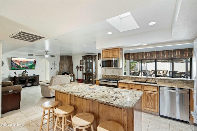 kitchen with stainless steel appliances, a sink, visible vents, open floor plan, and a center island