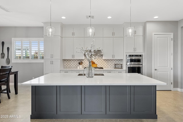 kitchen featuring white cabinetry, a large island with sink, and hanging light fixtures