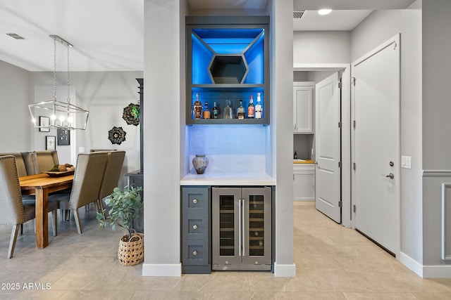 bar with gray cabinets, a notable chandelier, wine cooler, and hanging light fixtures