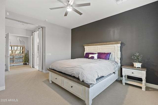 carpeted bedroom with ceiling fan and a barn door