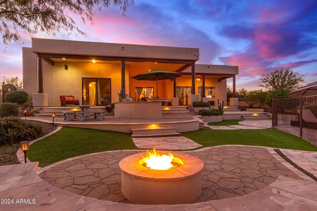 back house at dusk with a fire pit and a patio