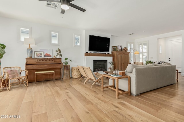 living room featuring light wood-style flooring, visible vents, and a healthy amount of sunlight