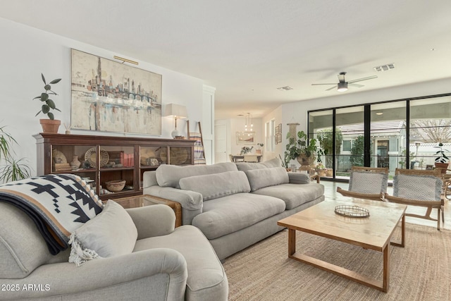 living area featuring visible vents and ceiling fan with notable chandelier