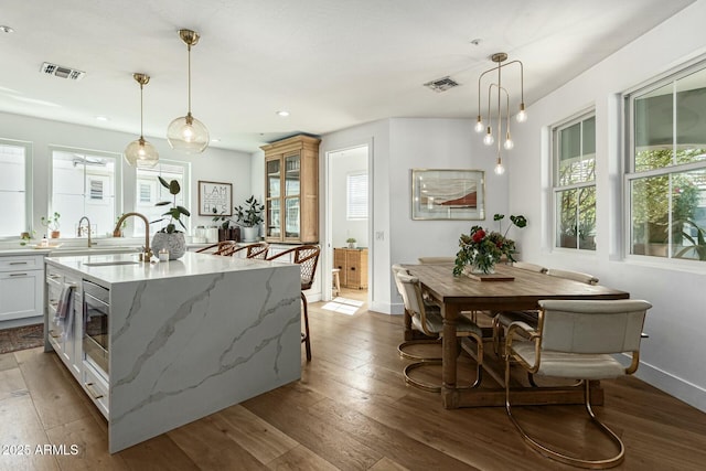 kitchen with hanging light fixtures, visible vents, and white cabinets