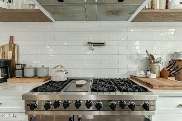 kitchen featuring tasteful backsplash, high end stainless steel range, white cabinetry, and light stone countertops