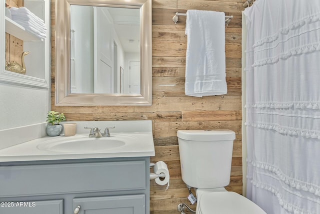 bathroom featuring wood walls, vanity, and toilet