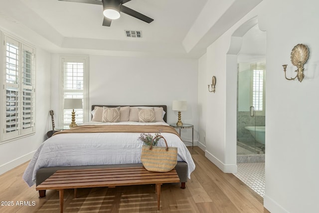 bedroom featuring light wood-style floors, a raised ceiling, and visible vents