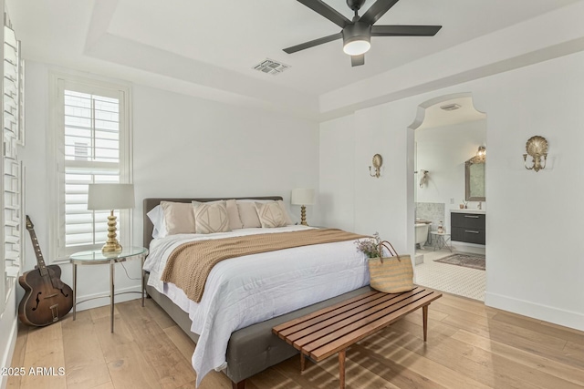 bedroom featuring hardwood / wood-style floors, a raised ceiling, visible vents, and baseboards