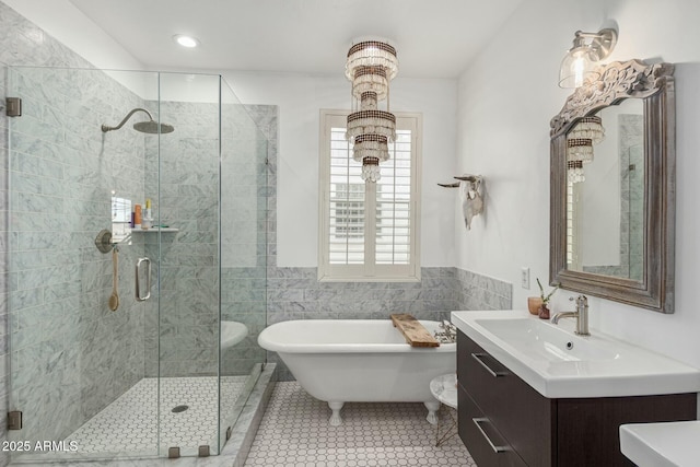 bathroom with tile walls, vanity, a shower stall, a freestanding tub, and tile patterned floors