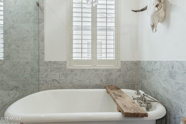 bathroom featuring a soaking tub, tile walls, and a wealth of natural light