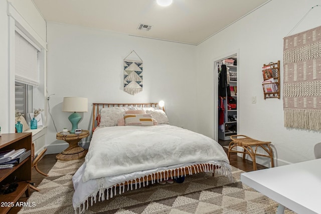 bedroom featuring a closet, visible vents, a spacious closet, and wood finished floors