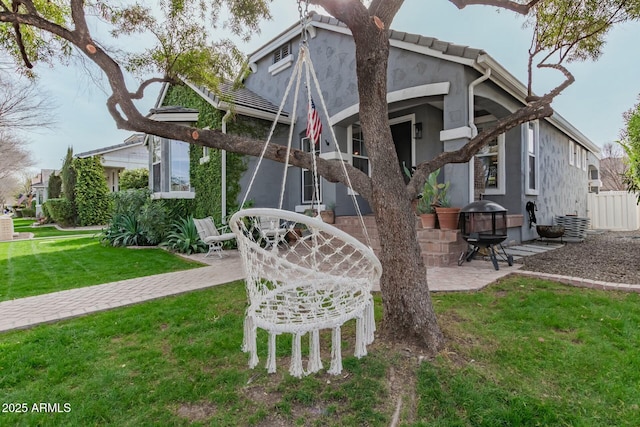 exterior space with a patio, a lawn, a tiled roof, and stucco siding