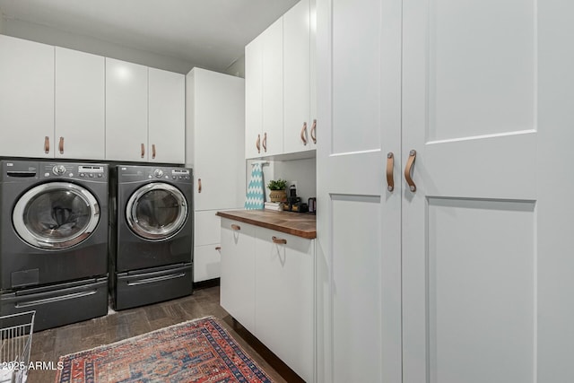 clothes washing area with washer and dryer, cabinet space, and wood finish floors