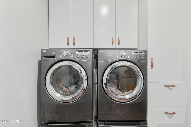 clothes washing area with separate washer and dryer and cabinet space