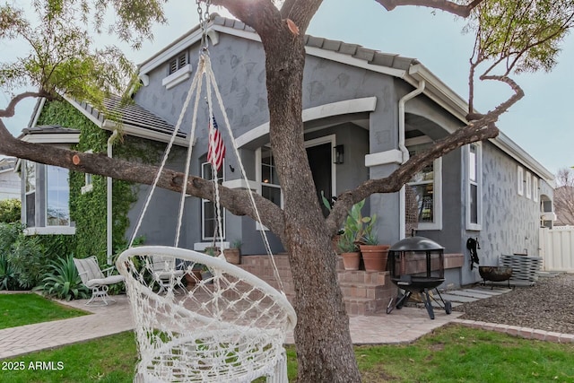 exterior space featuring a tile roof, a patio area, and stucco siding