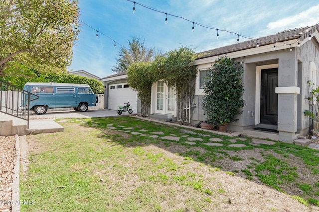 view of front of house with an attached garage, stucco siding, and a front yard