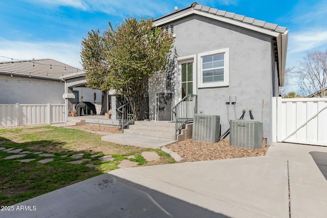 rear view of house with a patio area, stucco siding, fence, and central AC unit