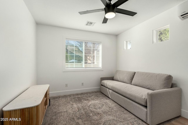 living area featuring a wall unit AC, visible vents, carpet flooring, ceiling fan, and baseboards