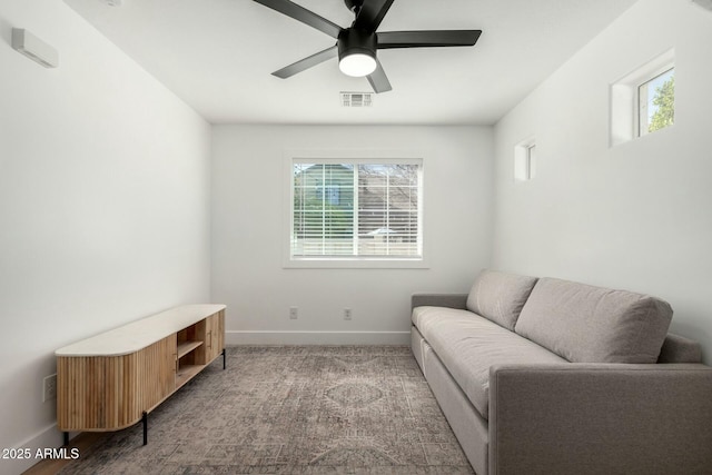 living area featuring carpet floors, visible vents, baseboards, and a ceiling fan