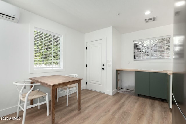 dining room with baseboards, visible vents, wood finished floors, and a wall mounted AC