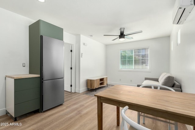 interior space featuring light wood finished floors, baseboards, a ceiling fan, and an AC wall unit