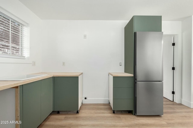 kitchen featuring light countertops, freestanding refrigerator, and green cabinetry