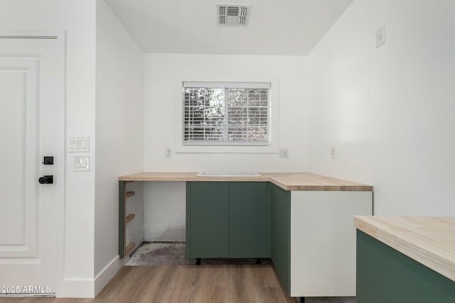 kitchen with wood counters, visible vents, baseboards, light wood-style floors, and green cabinetry