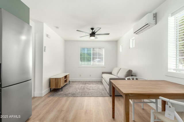 living room with a ceiling fan, a healthy amount of sunlight, light wood-style flooring, and a wall mounted AC