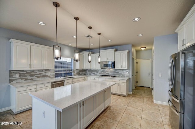 kitchen featuring a kitchen island, pendant lighting, sink, white cabinetry, and appliances with stainless steel finishes