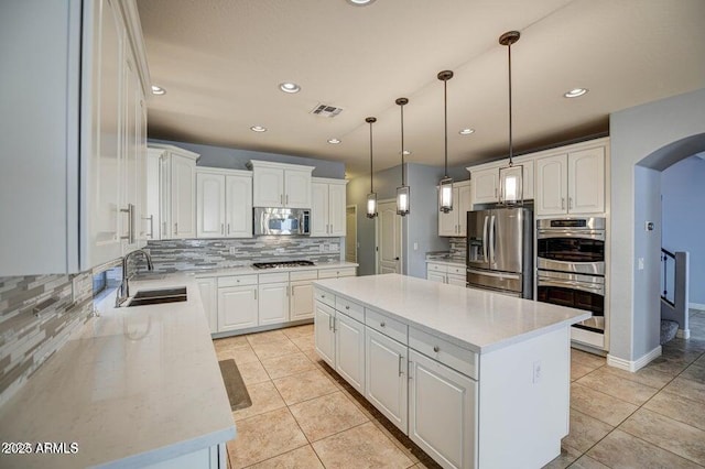 kitchen featuring white cabinetry, stainless steel appliances, a center island, pendant lighting, and sink