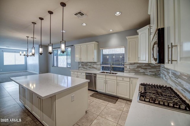 kitchen featuring backsplash, pendant lighting, a center island, sink, and appliances with stainless steel finishes