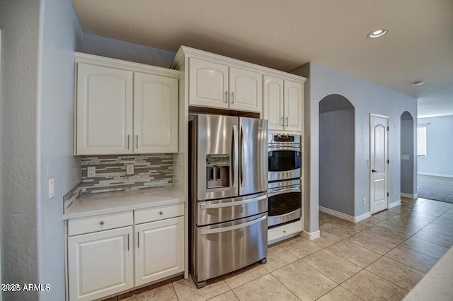 kitchen with light tile patterned floors, white cabinets, appliances with stainless steel finishes, and tasteful backsplash