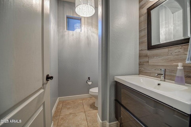 bathroom with toilet, vanity, tile patterned flooring, and a notable chandelier