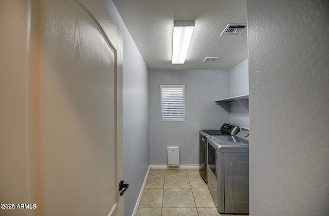 laundry room featuring light tile patterned flooring, separate washer and dryer, and a textured ceiling