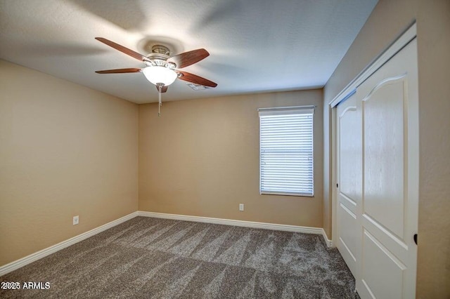 spare room featuring dark colored carpet and ceiling fan