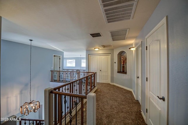 hallway with vaulted ceiling, dark colored carpet, and a notable chandelier